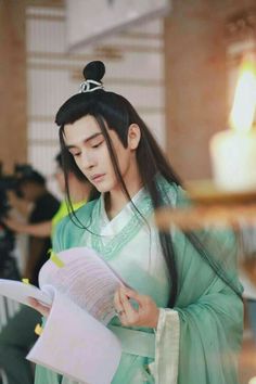 Liao Jingfeng dressed as Lord Puchi reads a script during production of Ashes of Love